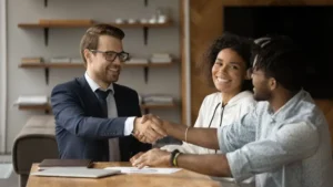 couple shaking hands with auto refinance representative